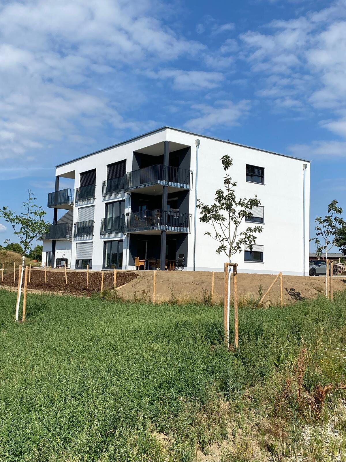Mehrfamilienhaus am Hammerberg mit BERGER Projektschild auf der Grünfläche